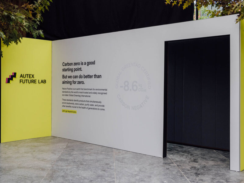 A phot oof an isntallation at an event, showcasing a wool acosutic panel with messaging printed on the side giving an isnight into the efforts to create a nature positive solution.